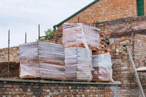 Construction site showing stacks of wrapped brick pallets in plastic sheeti.. Stock Photos