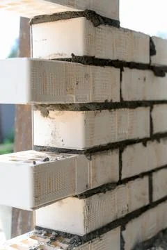 Construction site showing white bricks being laid with mortar in sunlight Stock Photos