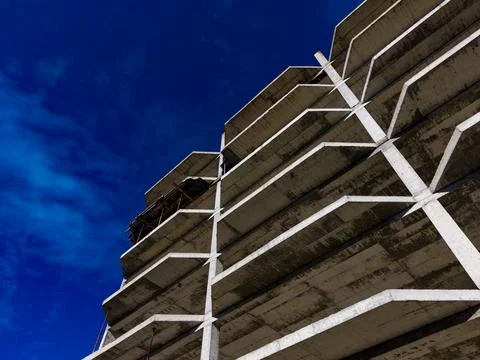 Construction site shows concrete framework of building against blue sky during Stock Photos