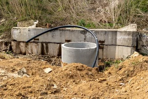A construction site shows a concrete pipe surrounded by dirt and grass next.. 스톡 사진