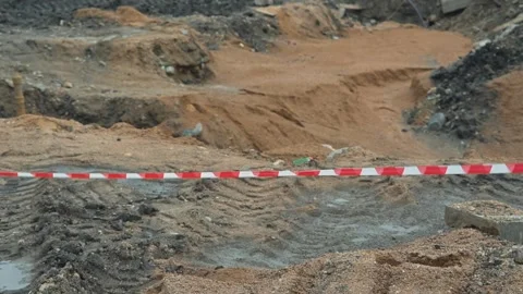 A construction site shows earth being moved as workers clear the ground. Red and 库存影片 344675850