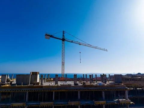 A construction site shows a large crane lifting materials under a clear blue  Stock Photos