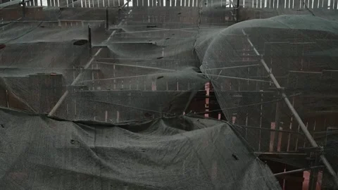 The construction site shows large tarps covering unfinished structures. Workers Stock-Footage 339094789
