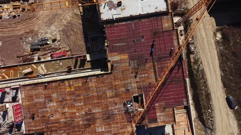 Construction site shows workers on roof of building with cranes and materials at Stock Footage 336576398