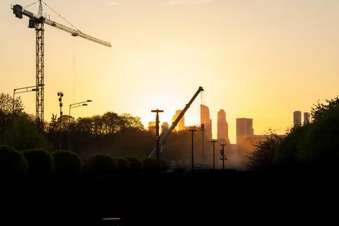 Construction site silhouette at sunset with cranes and city skyline in the Stock Photos