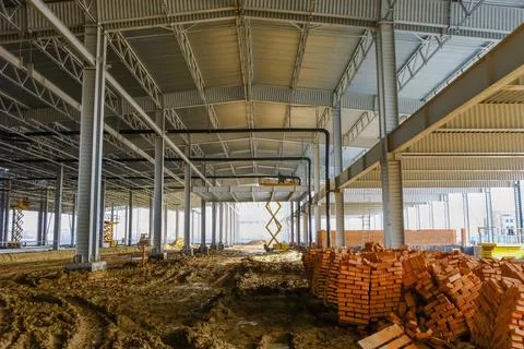Construction site of a spacious warehouse with scaffolding and stacked bricks Stock Photos