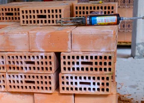 Construction site: stack of brick blocks and a loaded pistol cartidge resin. Stock Photos