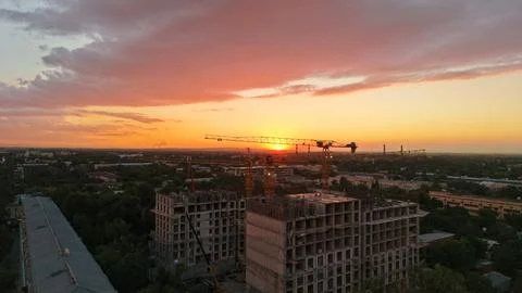 Construction site at sunset with cranes and buildings under development Stock Photos