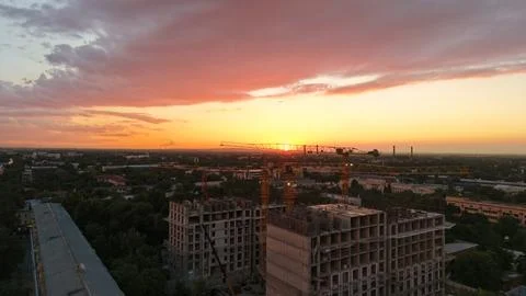 Construction site at sunset with cranes and buildings under development Stock Photos