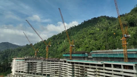 Construction Site Surrounded by Lush Green Hills Under Clear Blue Sky with Stock Footage 316450357