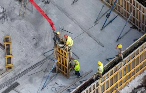 Construction site team using concrete pump truck hose to fill wall formwork Stock Photos