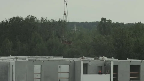 Construction site tower crane moving building material above concrete structure, Stock Footage 340387371