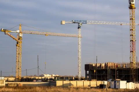 Construction site with tower cranes in a field against a dark blue sky Stock Photos