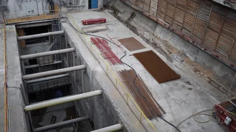 Construction site trench with deep concrete shaft and steel reinforcements stack Stock Footage 309655991