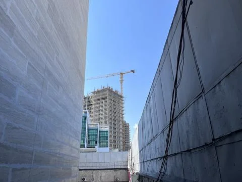 A construction site is visible between two large walls. A crane is working on Stock Photos