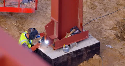 At a construction site, a welder welds a part to a huge red metal beam  Stock Footage 147637412