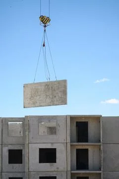 Construction site work. Lifting heavy concrete elements with crane at Fotos Stock