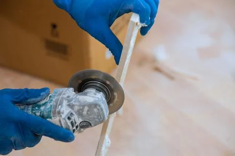 Construction site with worker cutting a tile using an circular saw Stock Photos