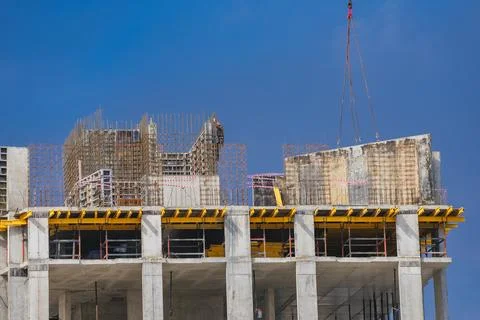 Construction site with a worker on a high-rise building, featuring concrete Stock Photos