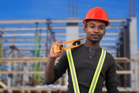 Construction site worker holding level tool and wearing red security hat helm Stock Photos