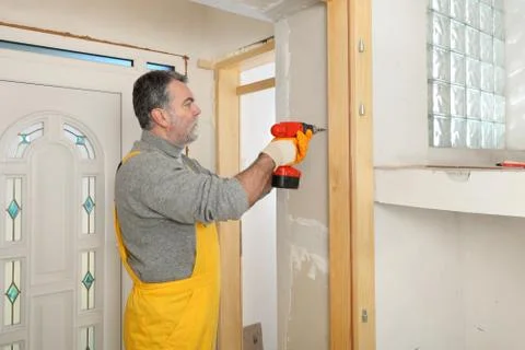 Construction site, worker installing gypsum board Фото