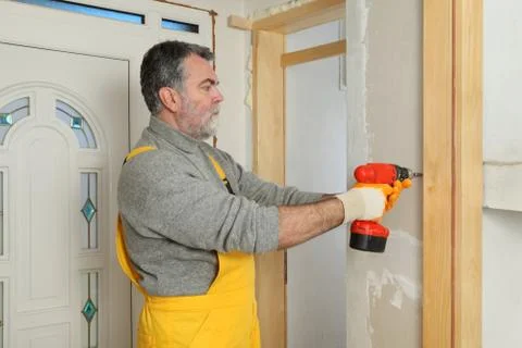 Construction site, worker installing gypsum board using electric tool Stock Photos