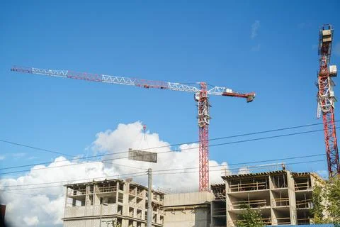 Construction site with a worker operating a tower crane moving a large concrete Stock Photos