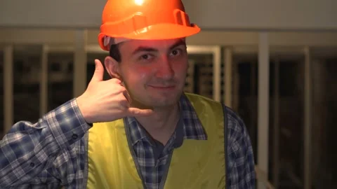 On a construction site, a worker or engineer or architect makes call me sign Stock Footage 89086063