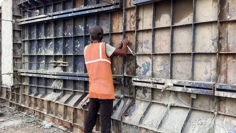 Construction site worker tightening bolts on a large metal formwork Stock Footage 336942735