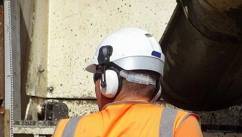Construction Site Worker Wearing Safety Helmet And Noise Reduction Earmuffs Stock Photos