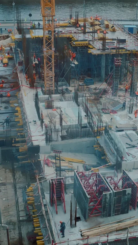 Construction site with workers and equipment near waterfront Stockbeeldmateriaal 318090419