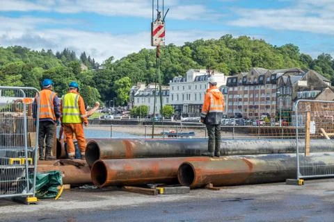 Construction site workers moving huge pipes Stock Photos