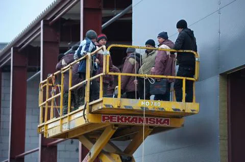 At the construction site. Workers standing on the platform of the truck mount Stock Photos