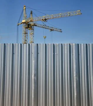 Construction site working crane behind iron fence. Stock Photos