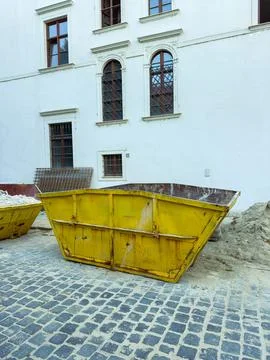 Construction site with yellow dumpster and building in the background at midd Stock Photos