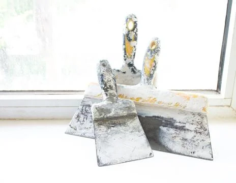 Construction spatulas lie on the windowsill after work Stock Photos