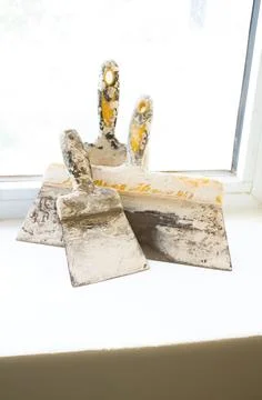Construction spatulas lie on the windowsill after work Stock Photos