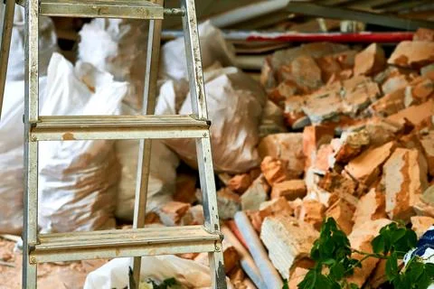Construction stepladder.Broken bricks, garbage in bags.Cleaning repairs Stock Photos