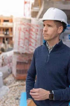Construction supervisor wearing a hard hat, looking intently at the buildin.. Stock Photos