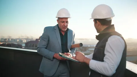 Construction, tablet and talking with men on rooftop for city planning or Stock Footage 337925777