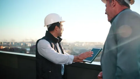 Construction, tablet screen and talk with men on rooftop for city planning or Stock Footage 337926395