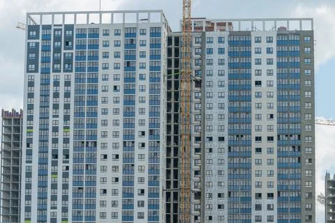 Construction of a tall building with many windows in an urban area during d.. Stock Photos