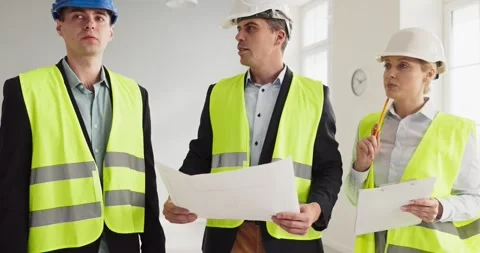 Construction team with blueprints and helmets inspecting interior renovation Stock Footage 341454536