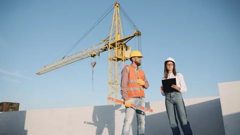 Construction team discusses project progress at a building site with crane Video stock 311306762