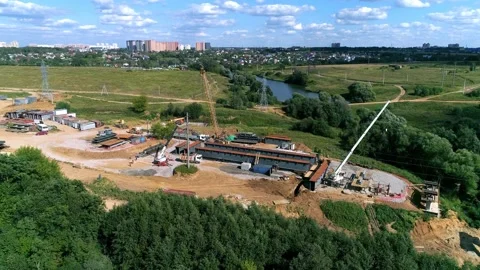 Construction team paving a new road and bridge across the stream - drone footage Stock Footage 142992054