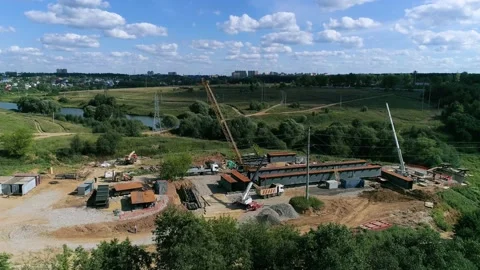Construction team paving a new road and bridge across the stream - drone footage Stock Footage 142992142