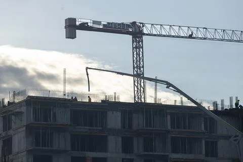 Construction team working to install metal components on rising concrete tower Stock Photos