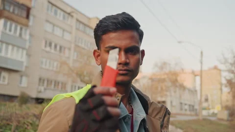 Construction technician inspects red handled tool outdoors near apartment Stock Footage 332504457