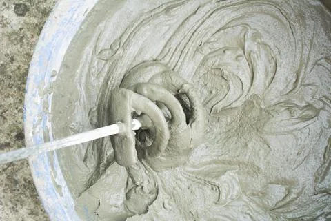 Construction technicians mixing concrete with electrical drill and mixer. Cem Stock Photos