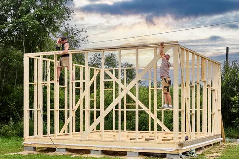 Construction of timber frame house on foundation of concrete blocks, two wo.. Stock Photos